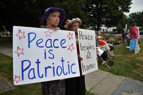 woman holding sign that says Peace is Patriotic